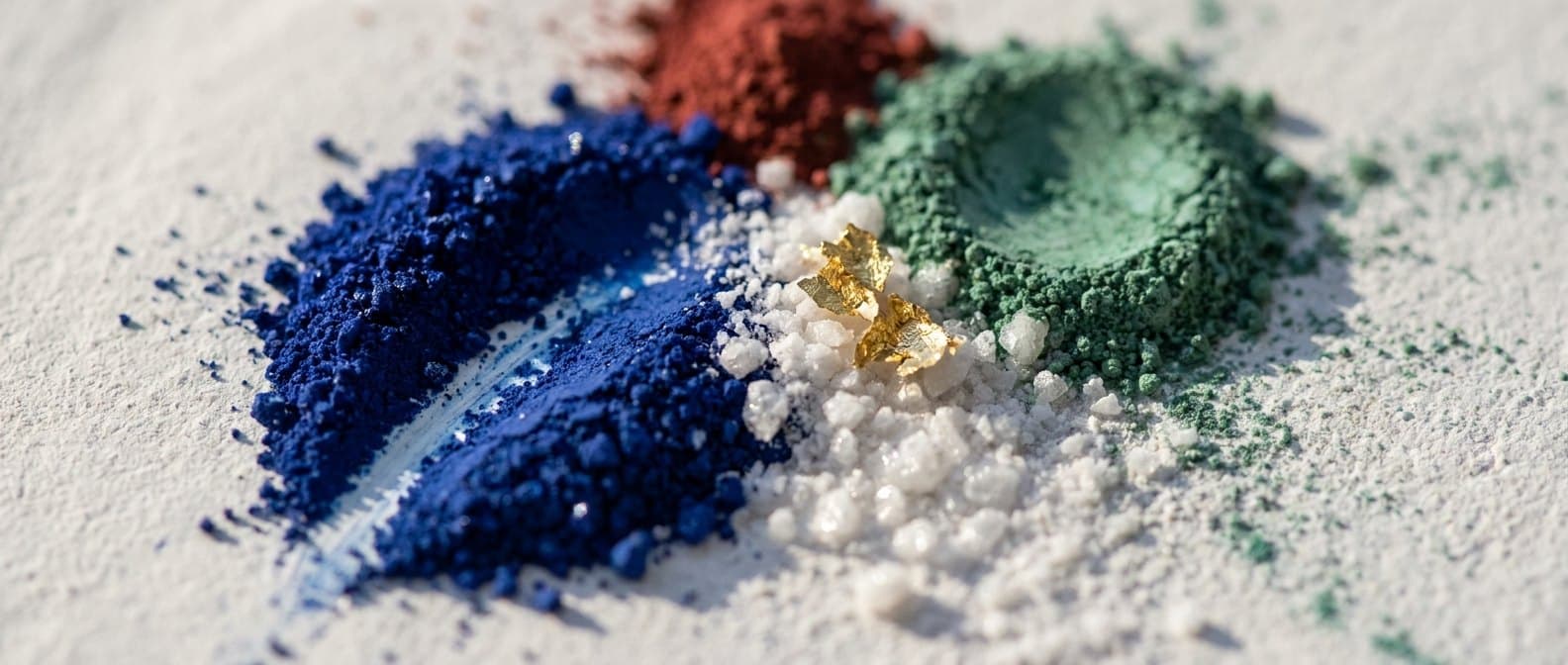 Rohe Mineralpigmente in Azuritblau, Grünspan und Zinnober neben Marmormehl und Blattgold